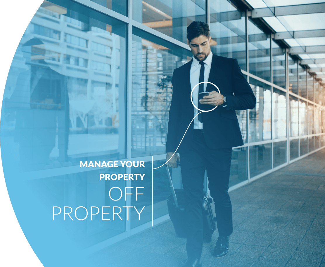 man in a suit walking with luggage checking on a hotel on cell phone